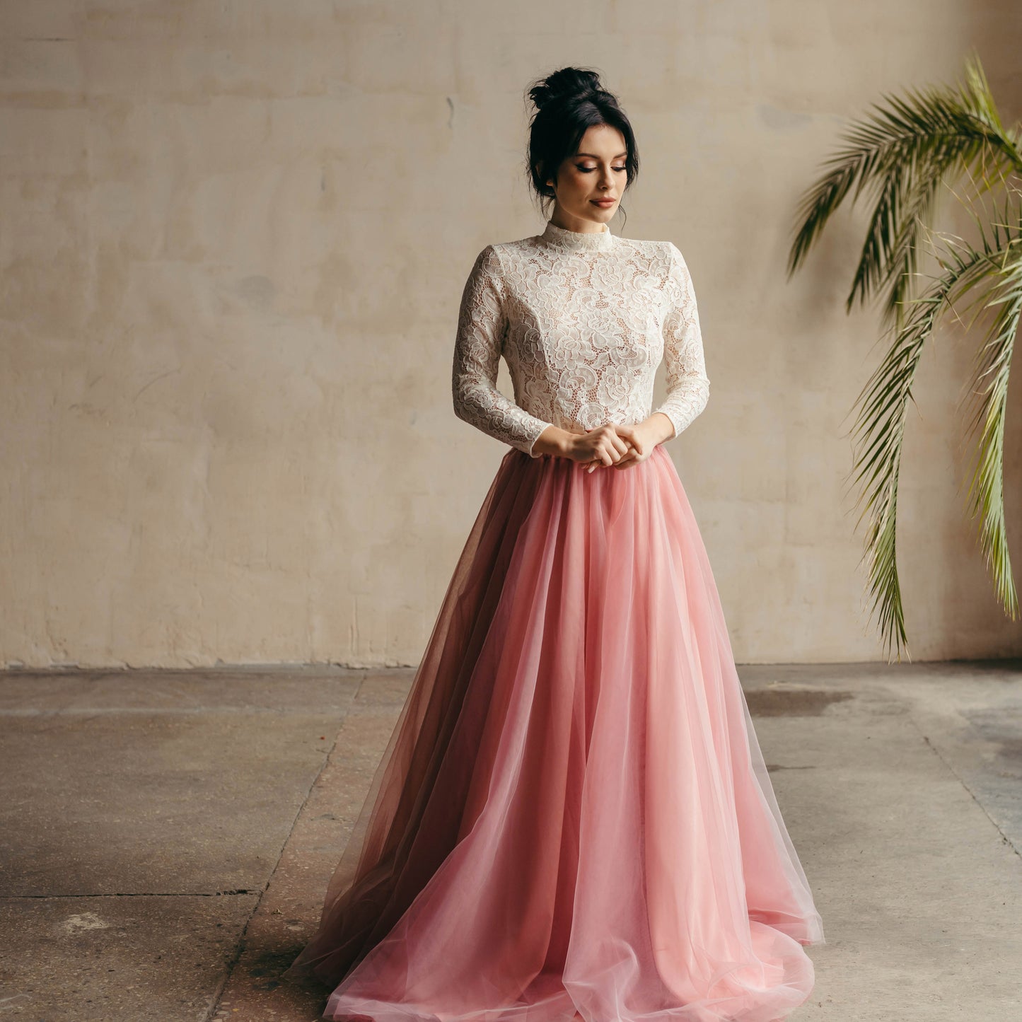 Bride playfully twirling in ivory long-sleeved lace top and vibrant berry pink tulle skirt—fun, fresh, and fashion-forward.