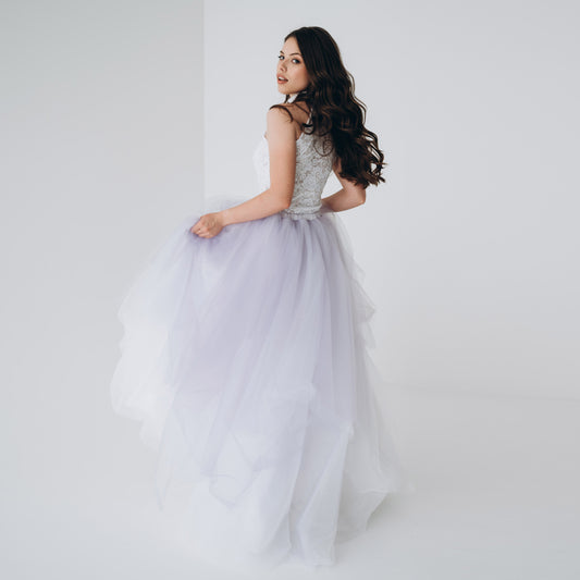 Bride in white and lavender ombré skirt twirling for romantic wedding photography.