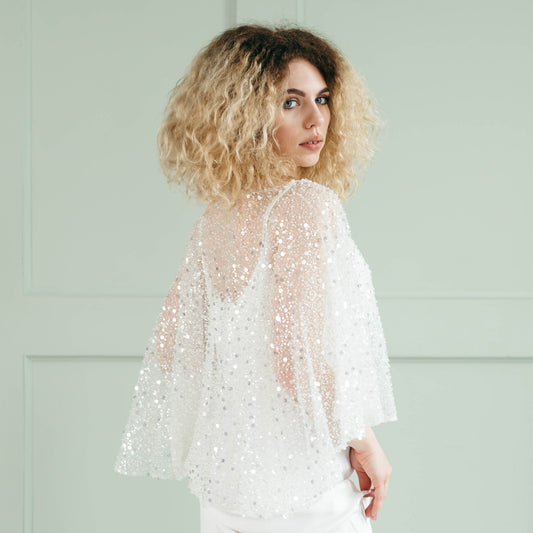 Side angle of model in shimmering bridal cape with silver bead embellishments