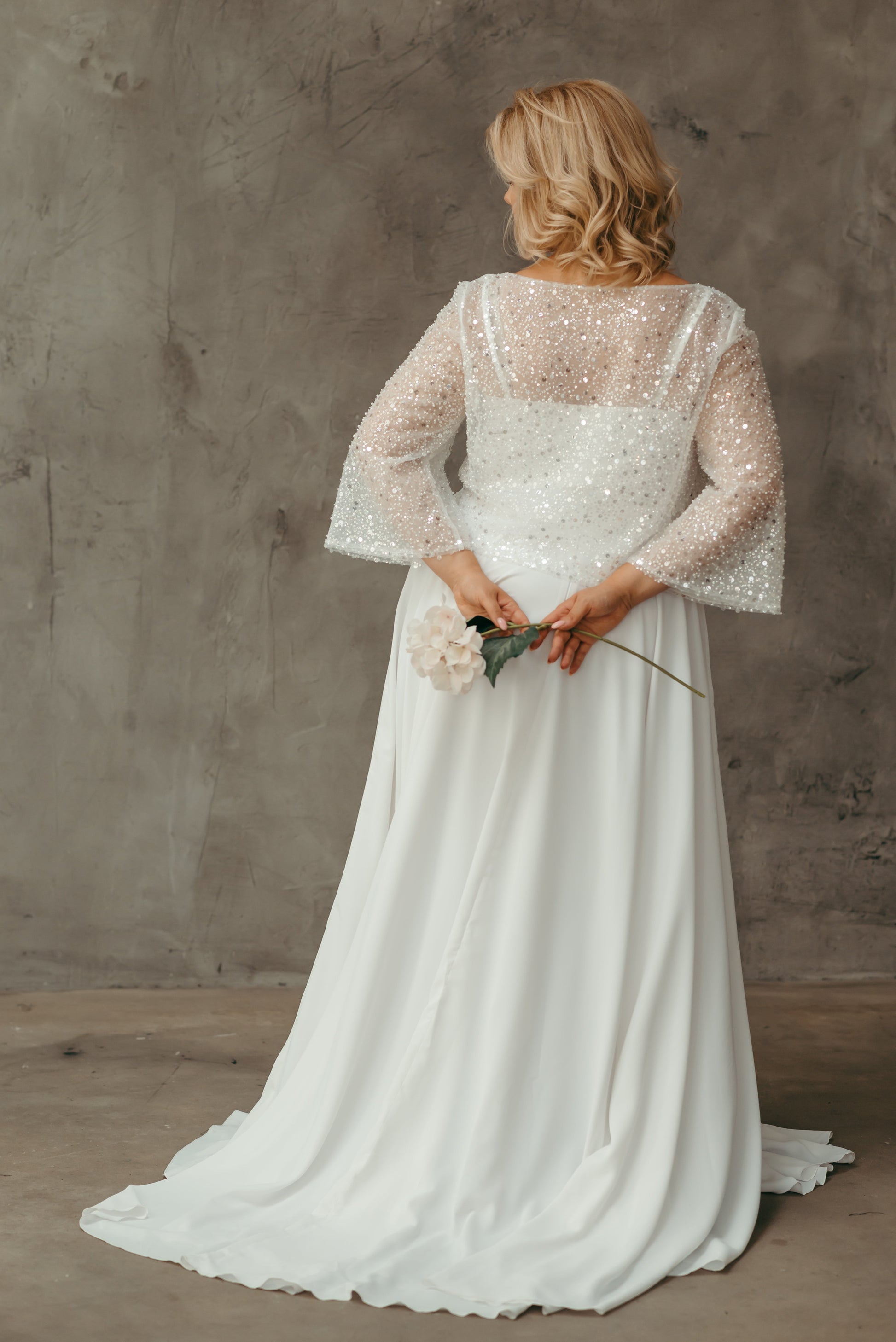 Rear view of bride in tulle beaded wedding top with soft drape – bridal topper styled with a white satin skirt.