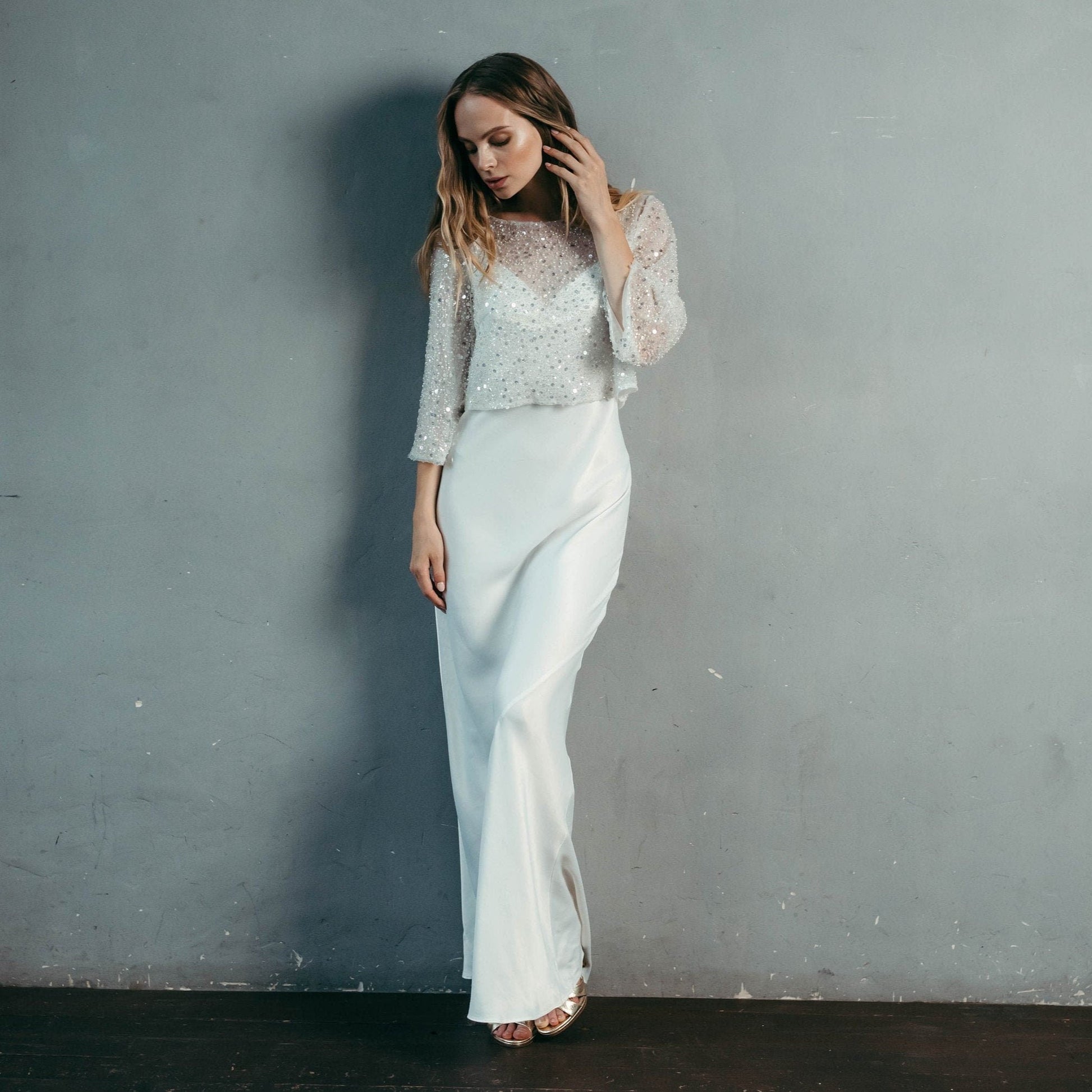 Detail shot of crystal and sequin embellishment on sheer tulle fabric – beaded bridal top material texture.