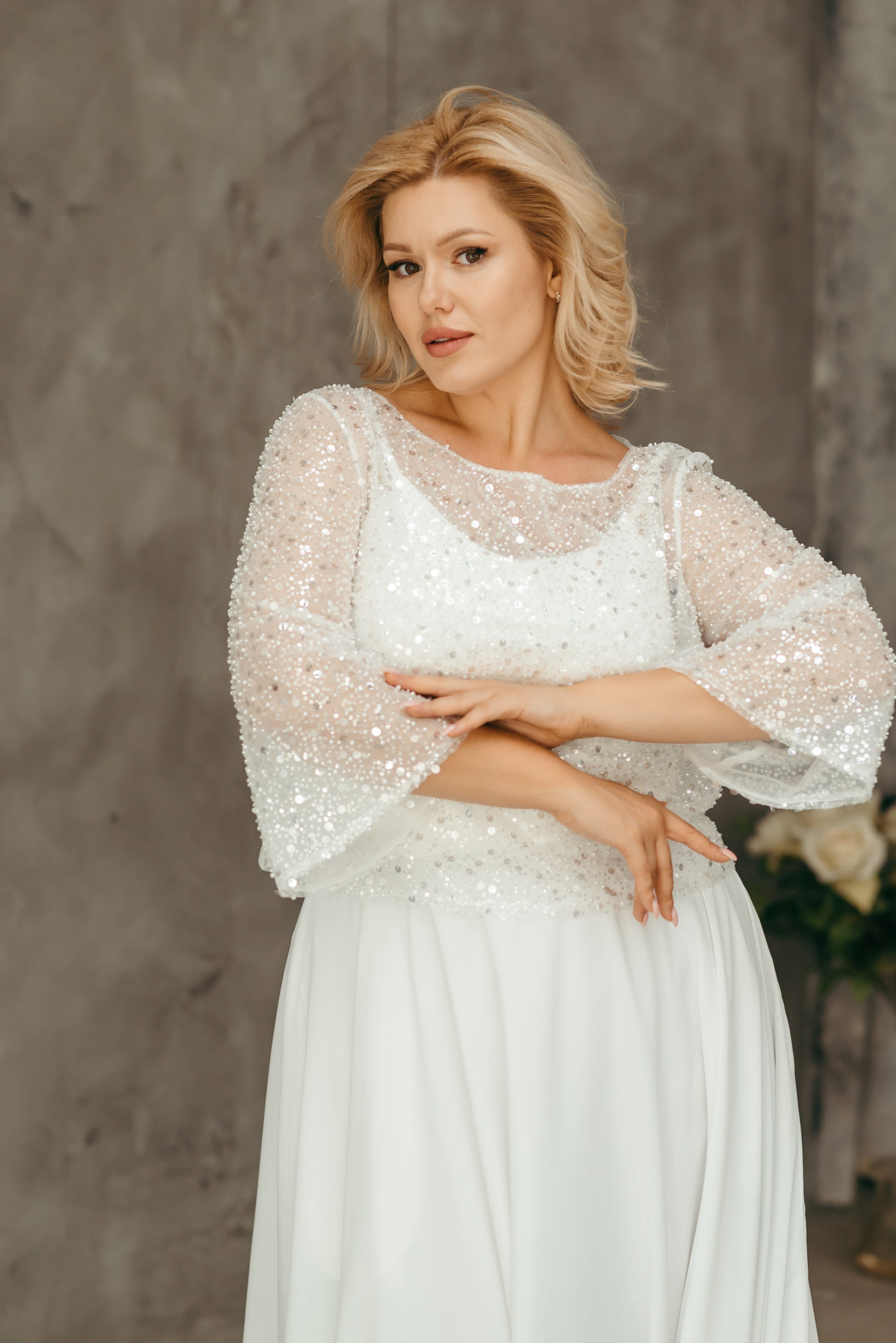 Bride in profile view wearing pearl and sequin bridal cover-up – soft wedding blouse with sparkle detail.