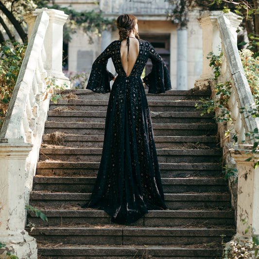 Back view of black lace wedding gown, worn on historic staircase with autumn foliage.