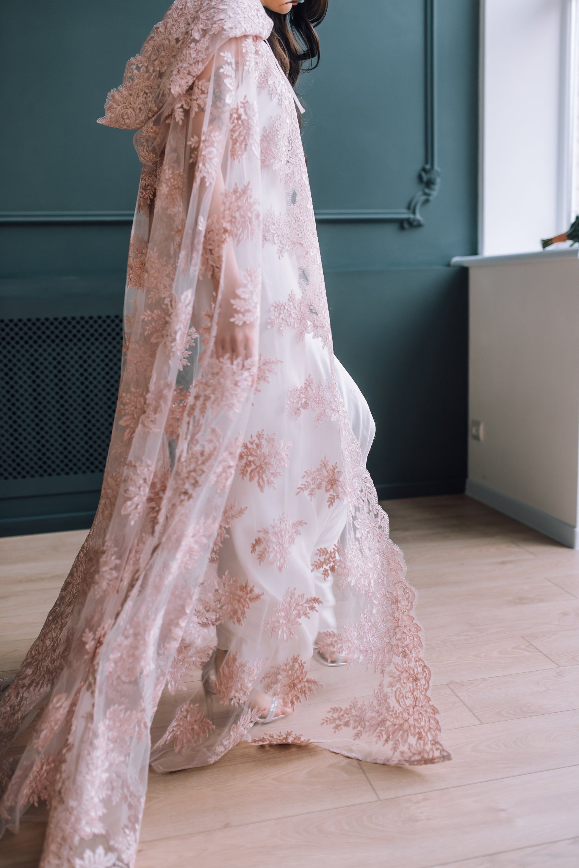 Side view of blush pink lace cloak with train and floral motif