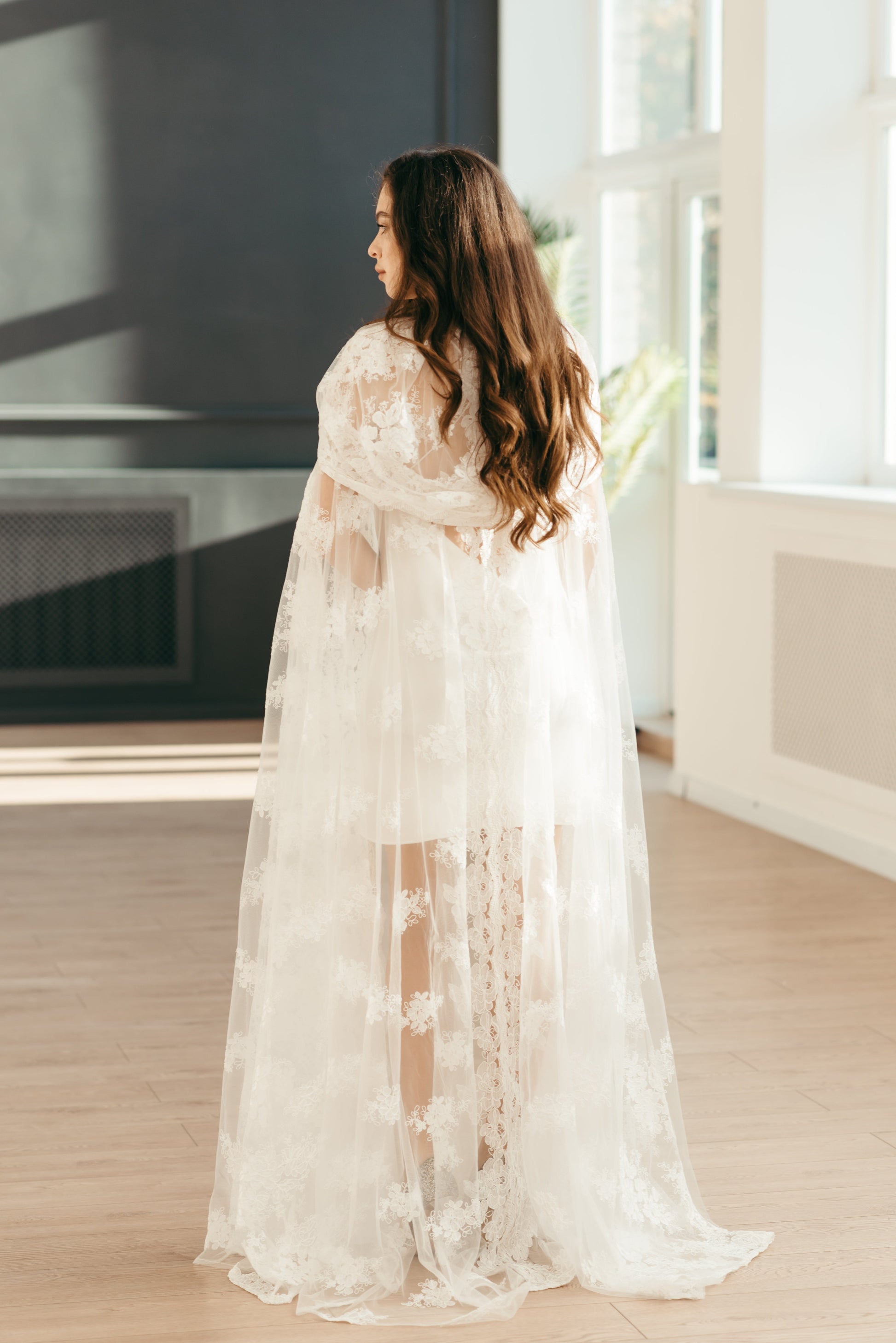 Bride walking in sheer ivory lace cloak with scalloped edges