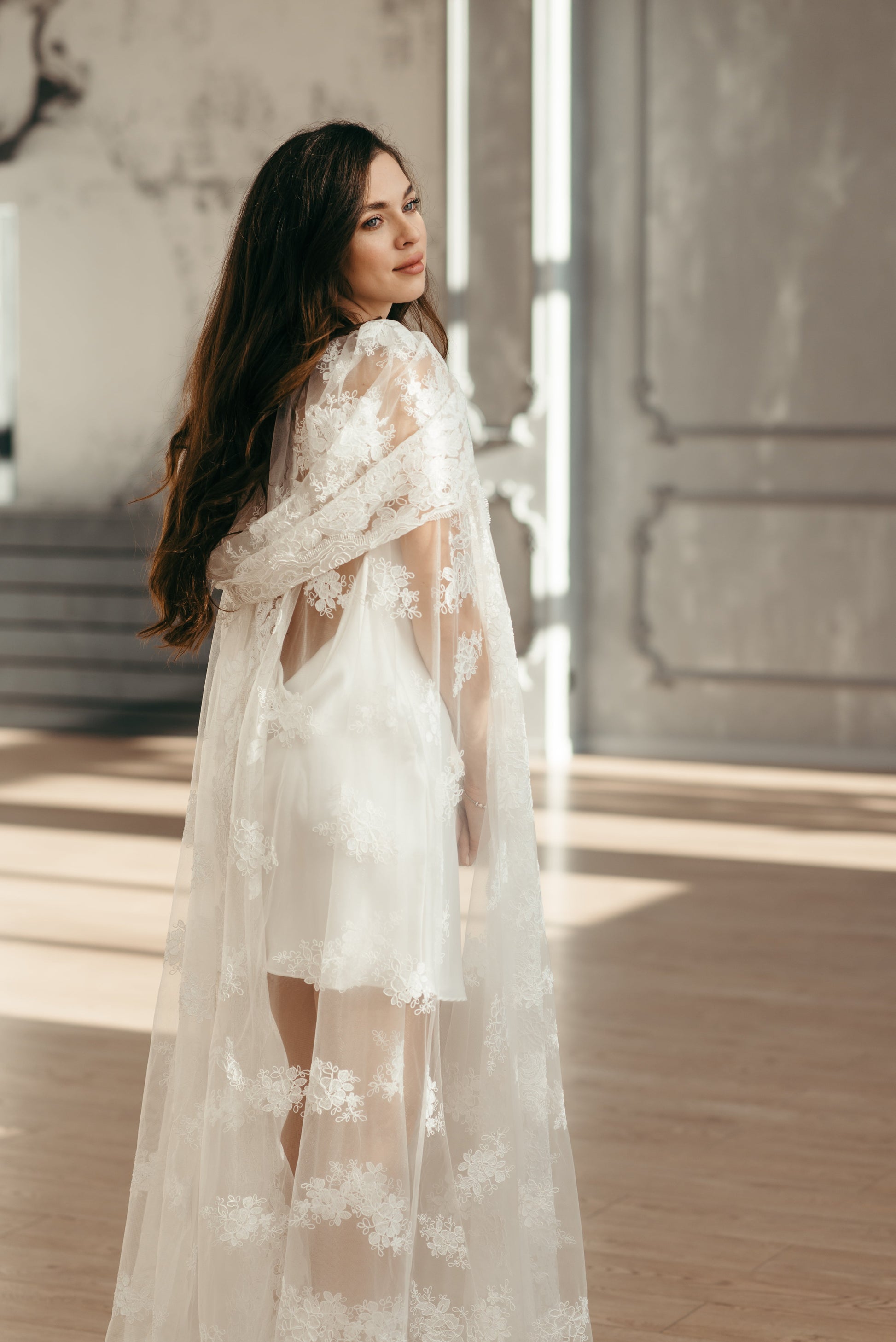 Model in ivory lace cape with long train and high neckline