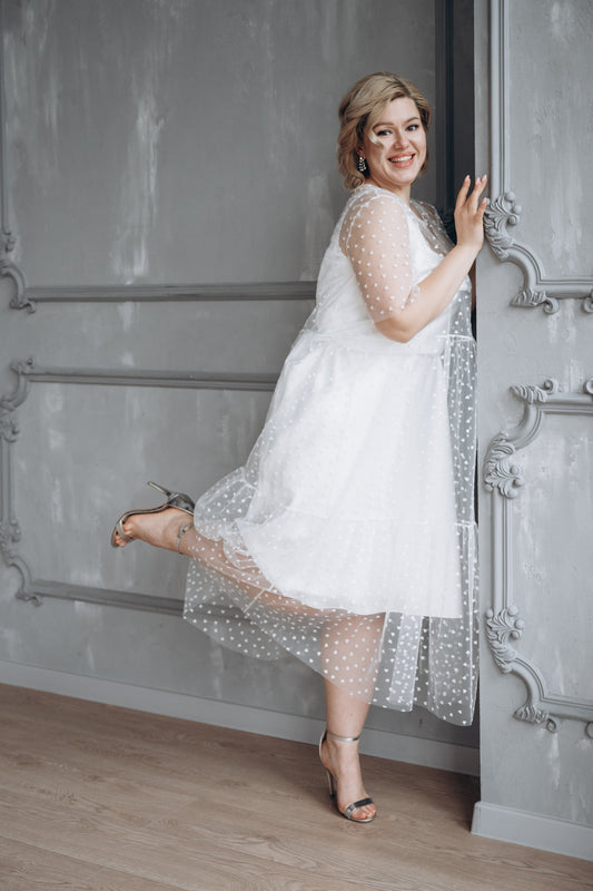 White heart pattern tulle dress, plus size model posing with leg lifted playfully.