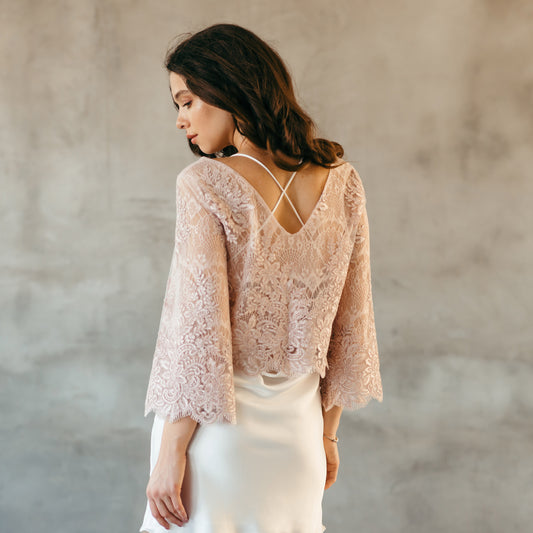 Blush pink lace wedding dress topper with floral pattern, bridal cover up with 3/4 long sleeves and cropped silhouette.