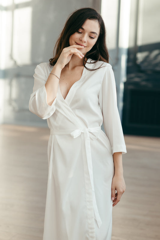 Bride wearing long white bridal kimono robe with wrap front, elegant minimalist design.