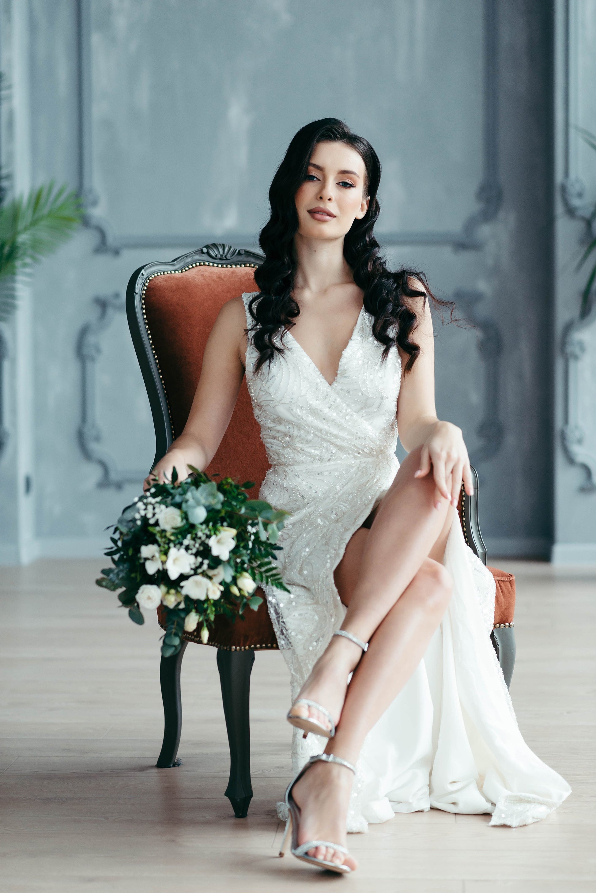 Bride modeling ivory sleeveless wedding dress with slit, showing movement and detail of beaded fabric.