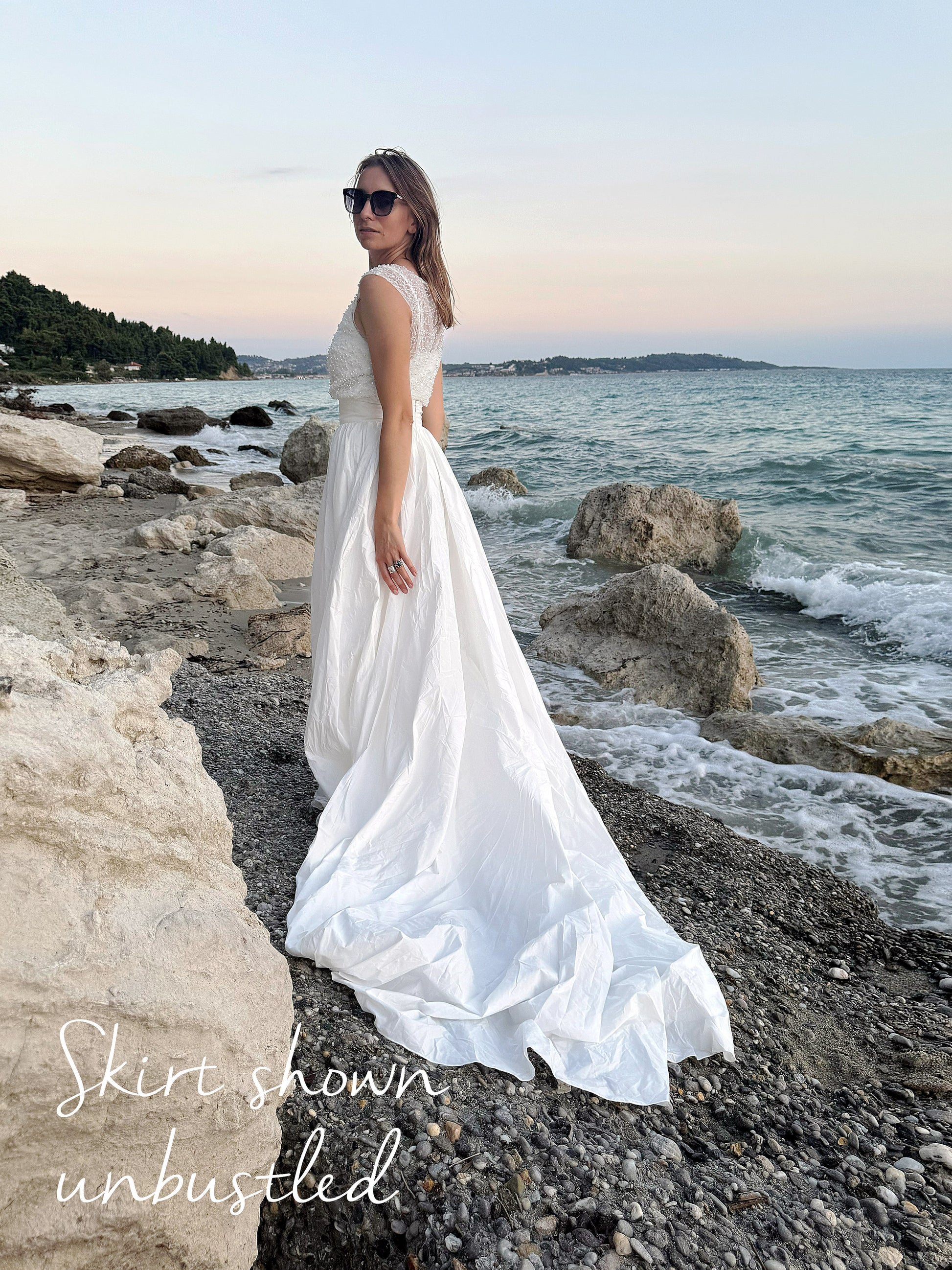 Bustled white skirt shown by the sea, highlighting subtle train feature