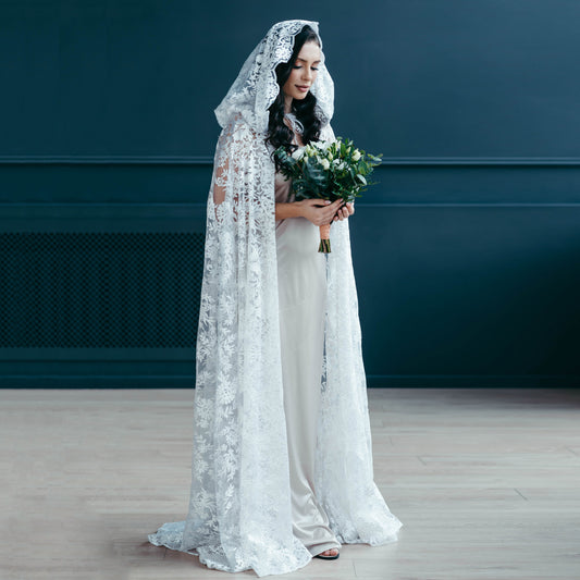 Bride in full-length white lace hooded veil holding bouquet