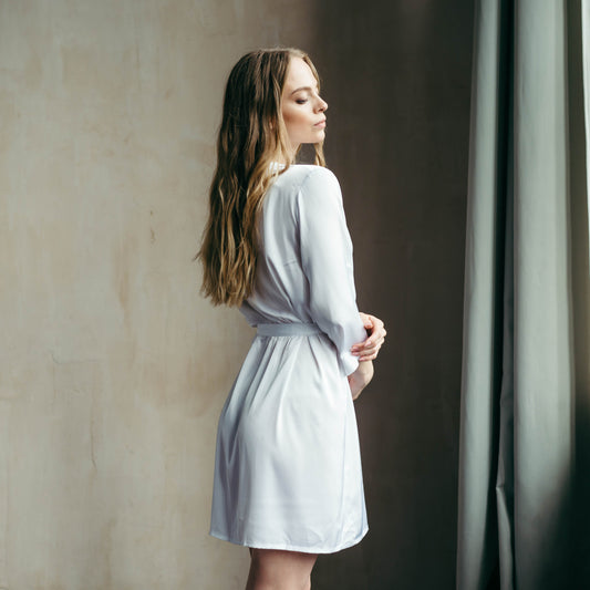 Model in a smooth semi-matte white satin robe above the knee, luxury bridal loungewear with wrap design.