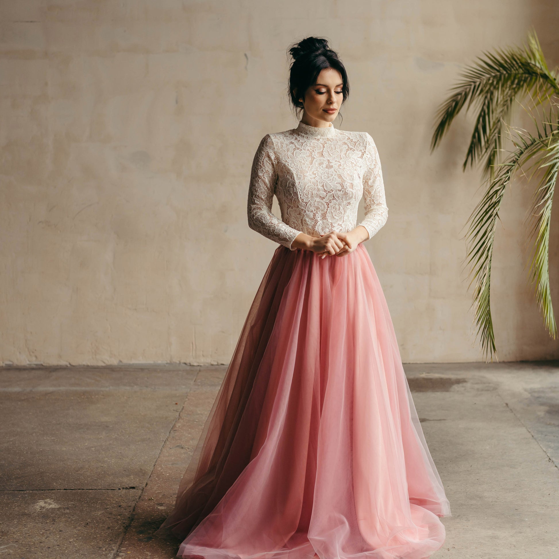 Bride playfully twirling in ivory long-sleeved lace top and vibrant berry pink tulle skirt—fun, fresh, and fashion-forward.