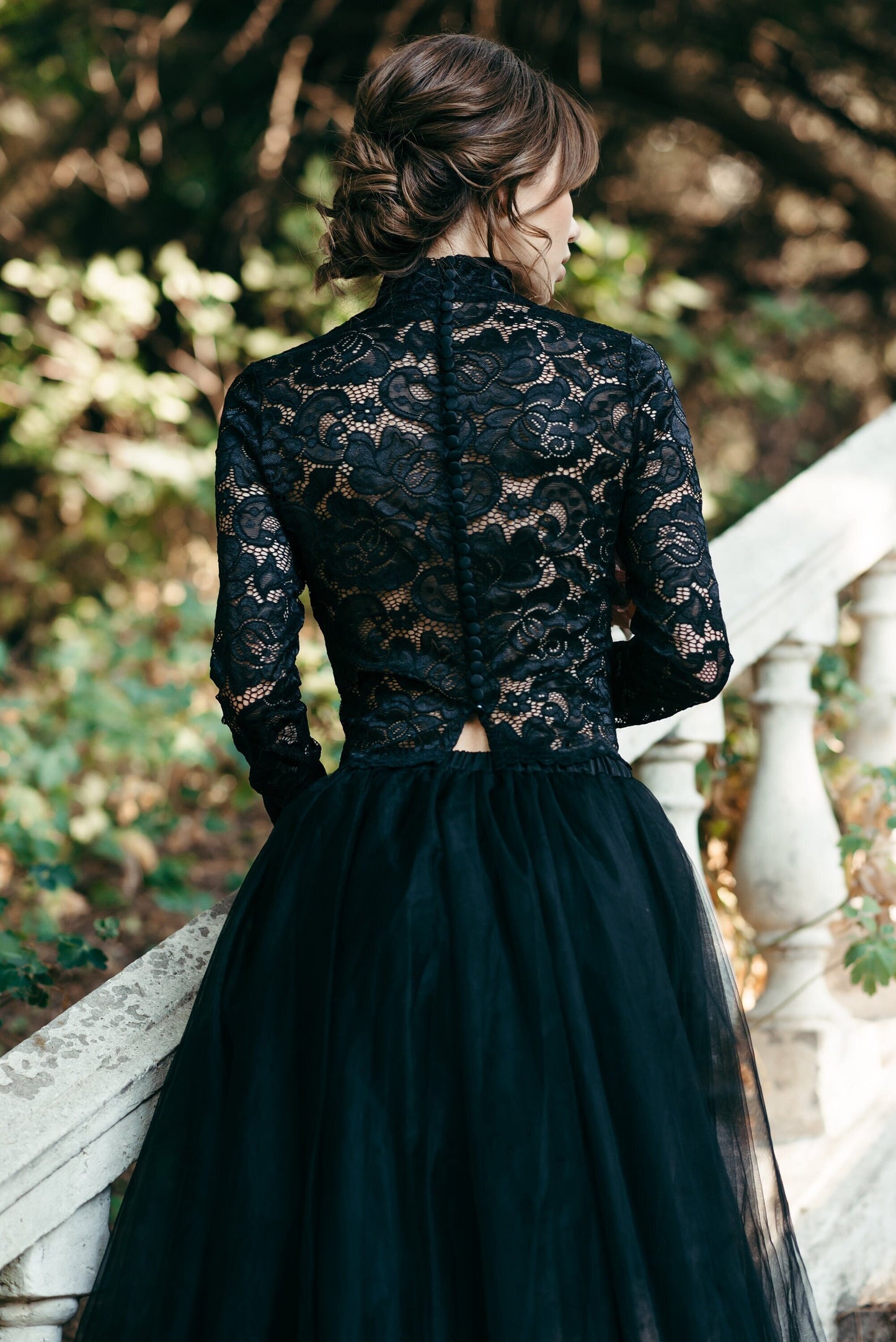  Rear view of gothic bridal look featuring black lace high neck top with delicate buttons, styled with a voluminous black tulle skirt.