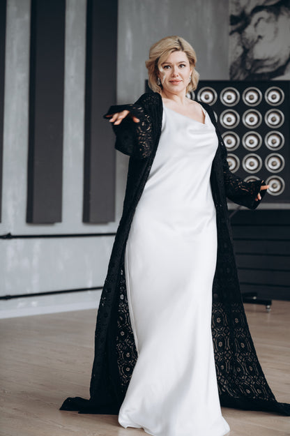 Bride is wearing a simple wedding dress paired with a handmade in the UK black macrame lece bridal cape with sleeves