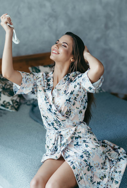 Two bridesmaids in matching floral satin robes, laughing together