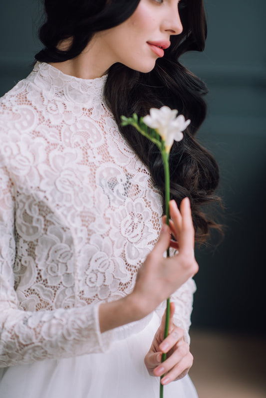 Close-up of the front design of ivory high neck bridal top, highlighting delicate construction and soft floral texture.