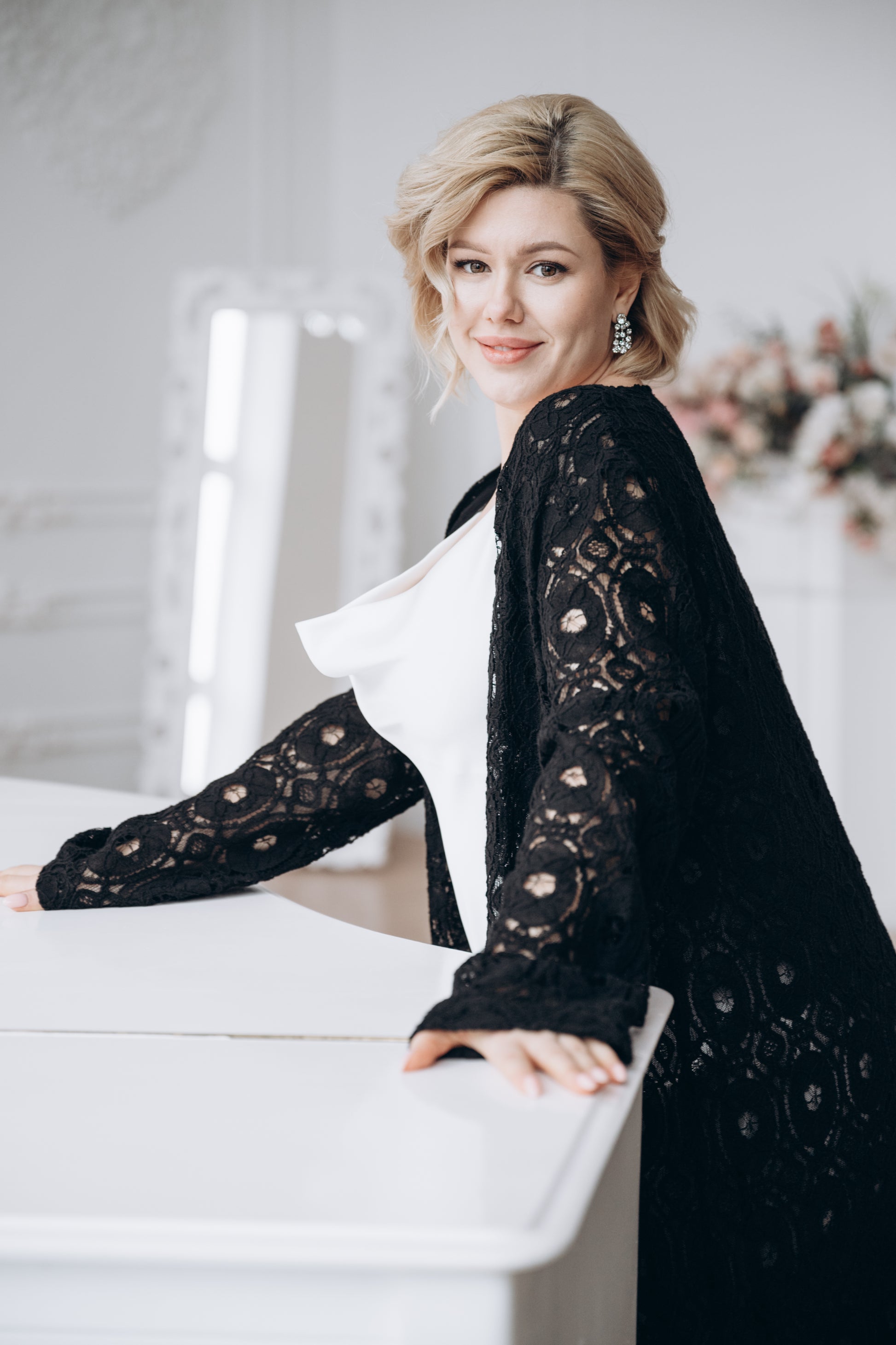 Bride wearing white dress with black macramé lace cape, standing