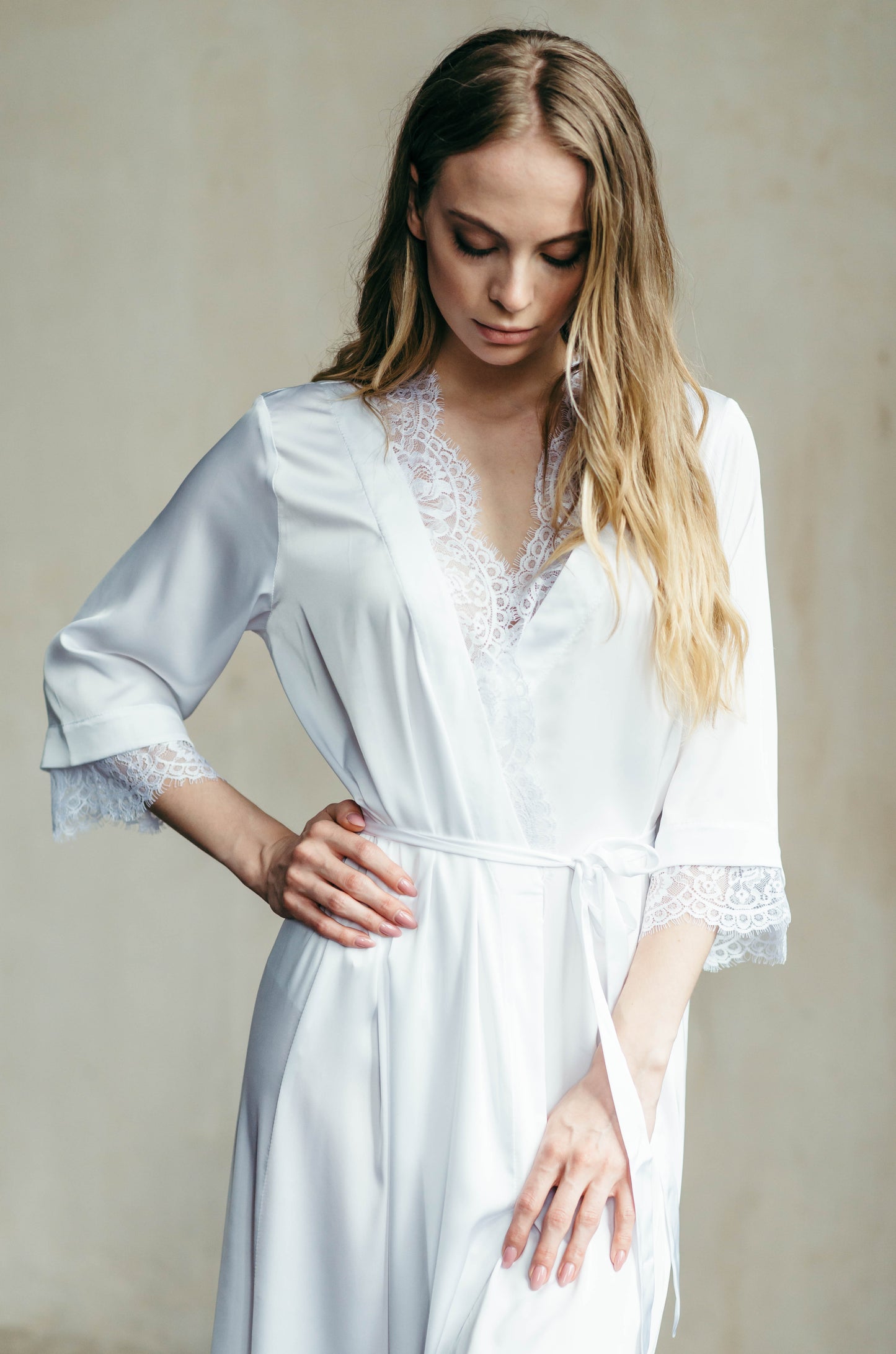 Detail of soft lace neckline on white satin bridal robe, elegant getting ready outfit.