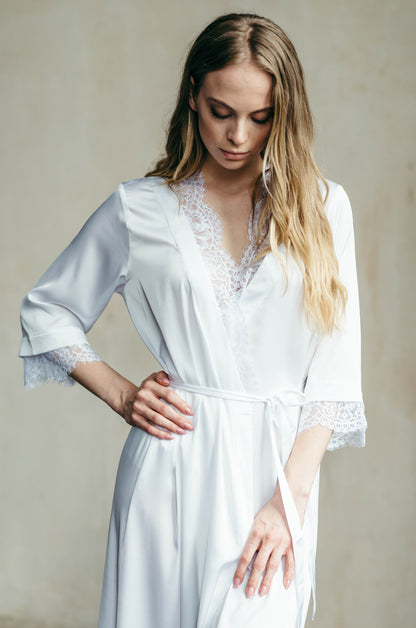 Detail of soft lace neckline on white satin bridal robe, elegant getting ready outfit.