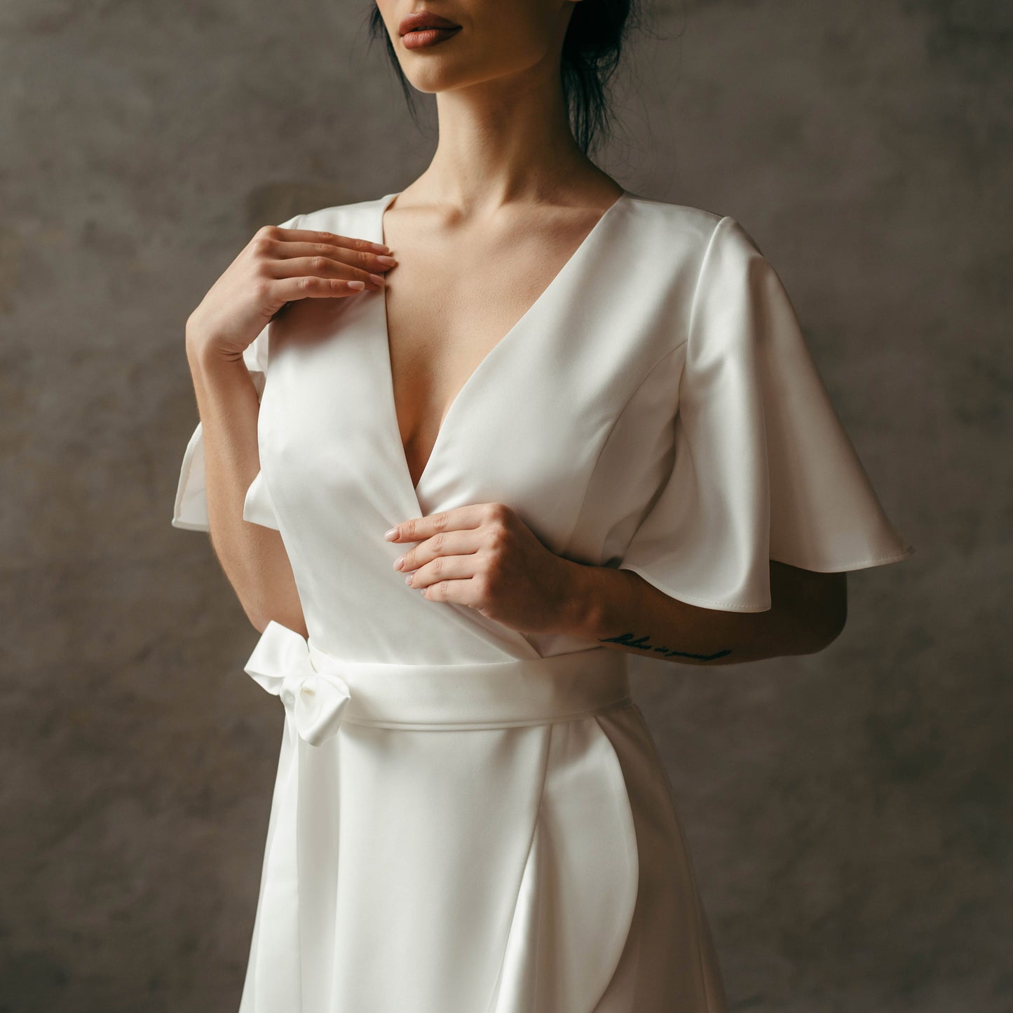Close-up of flutter sleeves and bodice detailing on ivory satin wedding dress.