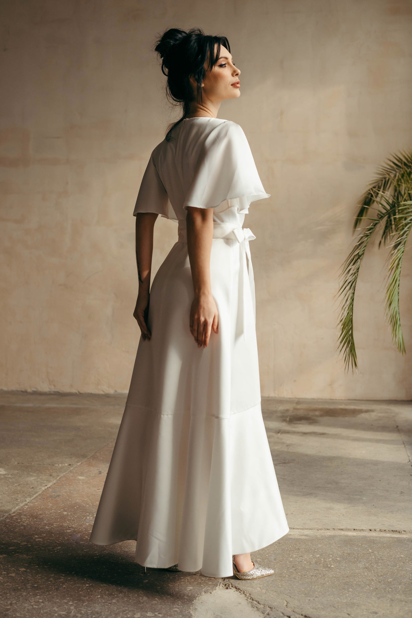 Side view of model showing the flowing asymmetrical hem and sleeve movement.