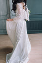Side profile of bride in ivory lace top holding bouquet, soft curls over shoulder