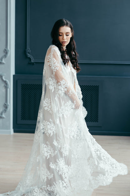 Ivory lace cape with delicate embellishments and flowing silhouette, designed for rewear and versatility.