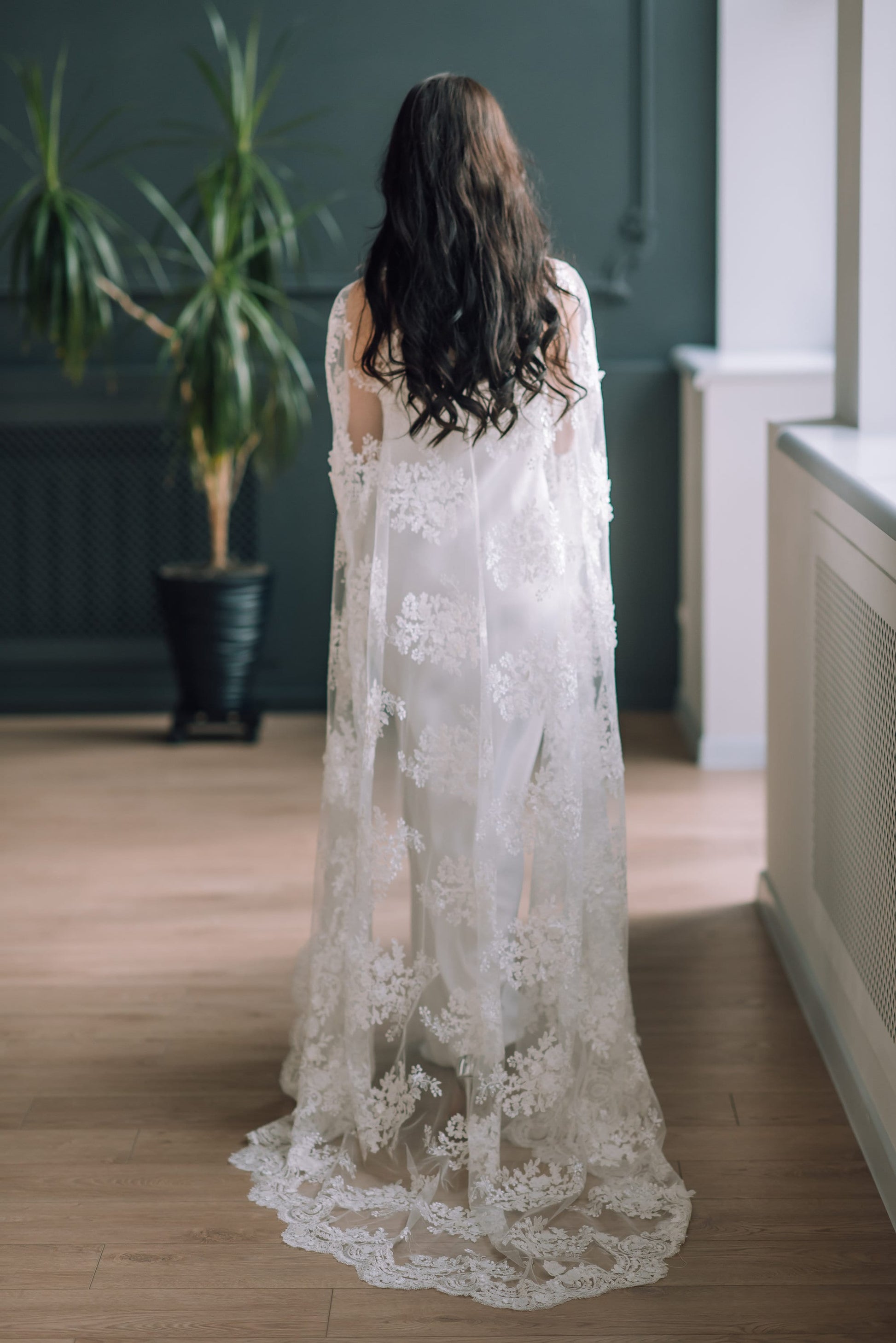 Ivory corded lace bridal cape with floral motif, 3D flowers, sequins, and soft beading for wedding day layering.
