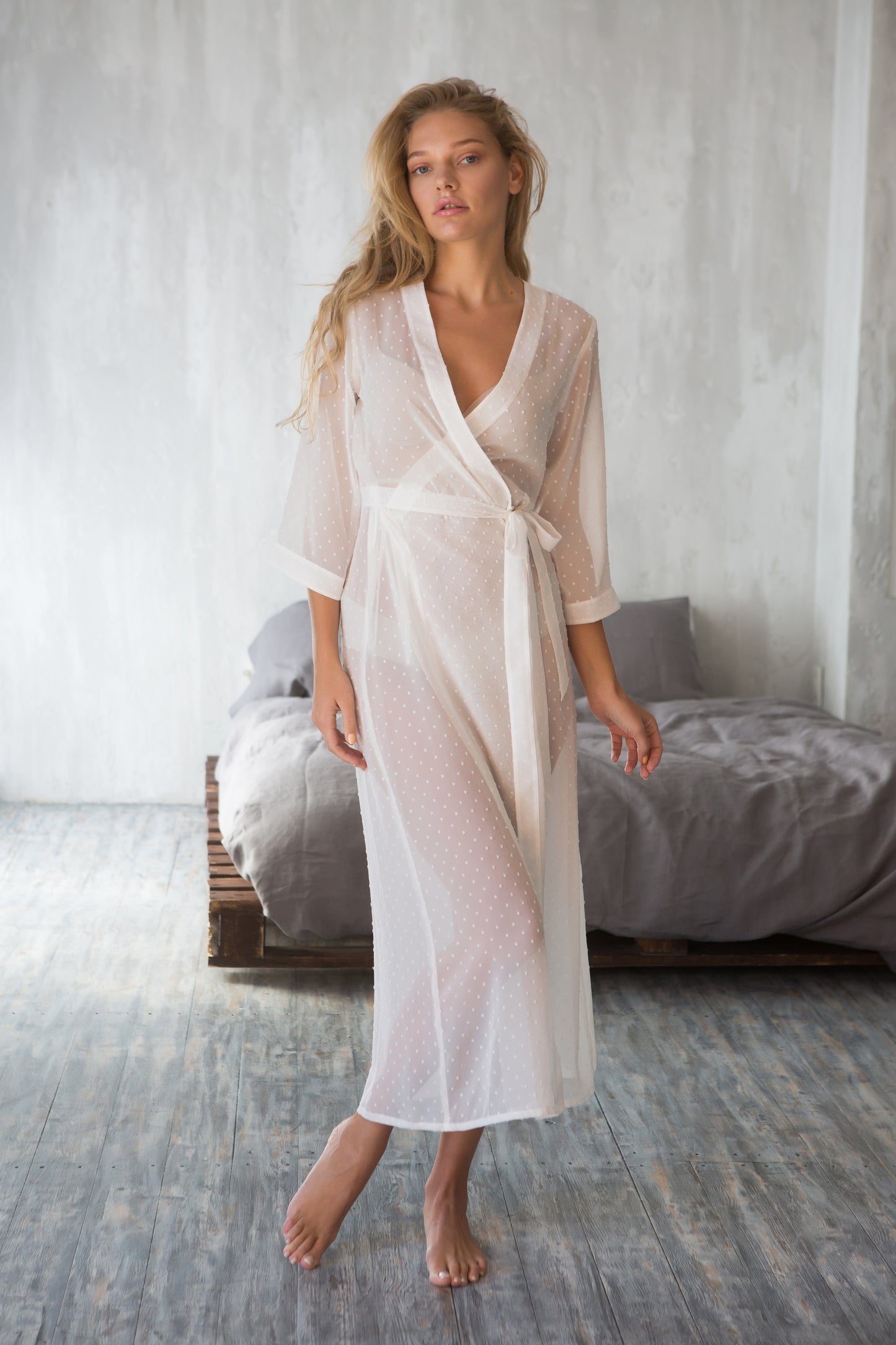 White sheer polka dot robe, styled on bed, three-quarter view