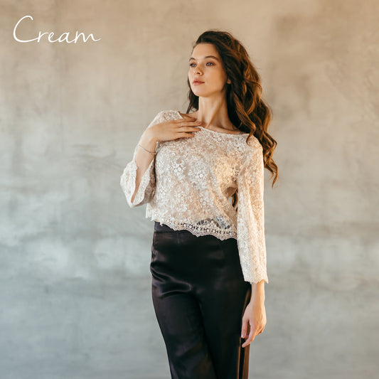 Cream lace top worn over black bridal trousers, model posing with hand lifted, ideal for editorial bridal styling.