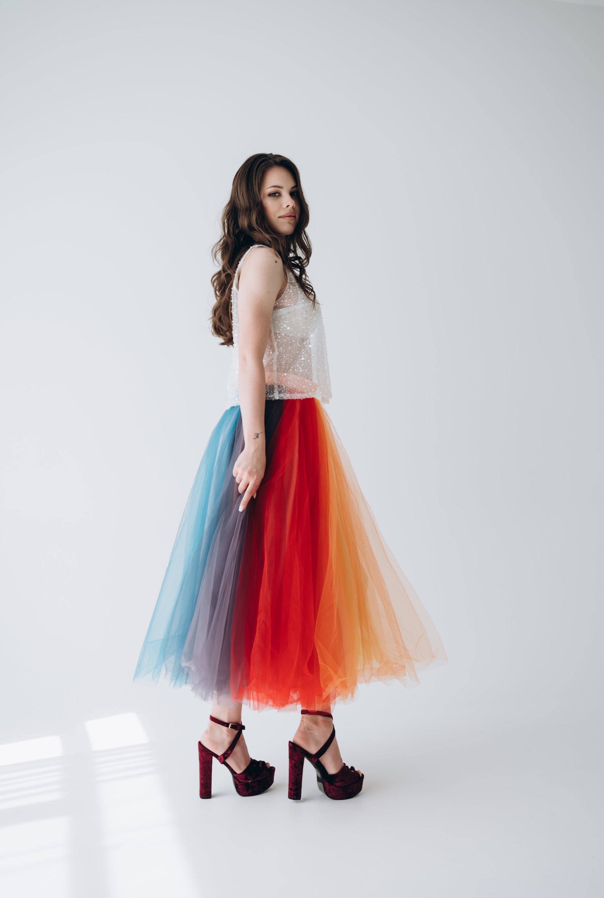 Woman wearing a colorful tulle rainbow skirt in tea length, paired with a white top