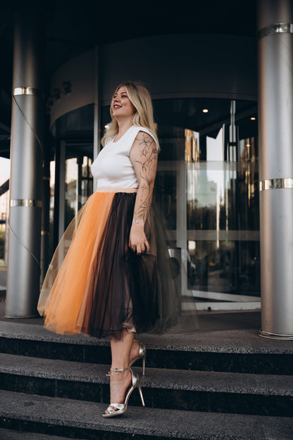 Woman in a white top and layered midi tulle skirt standing on steps of the registry office