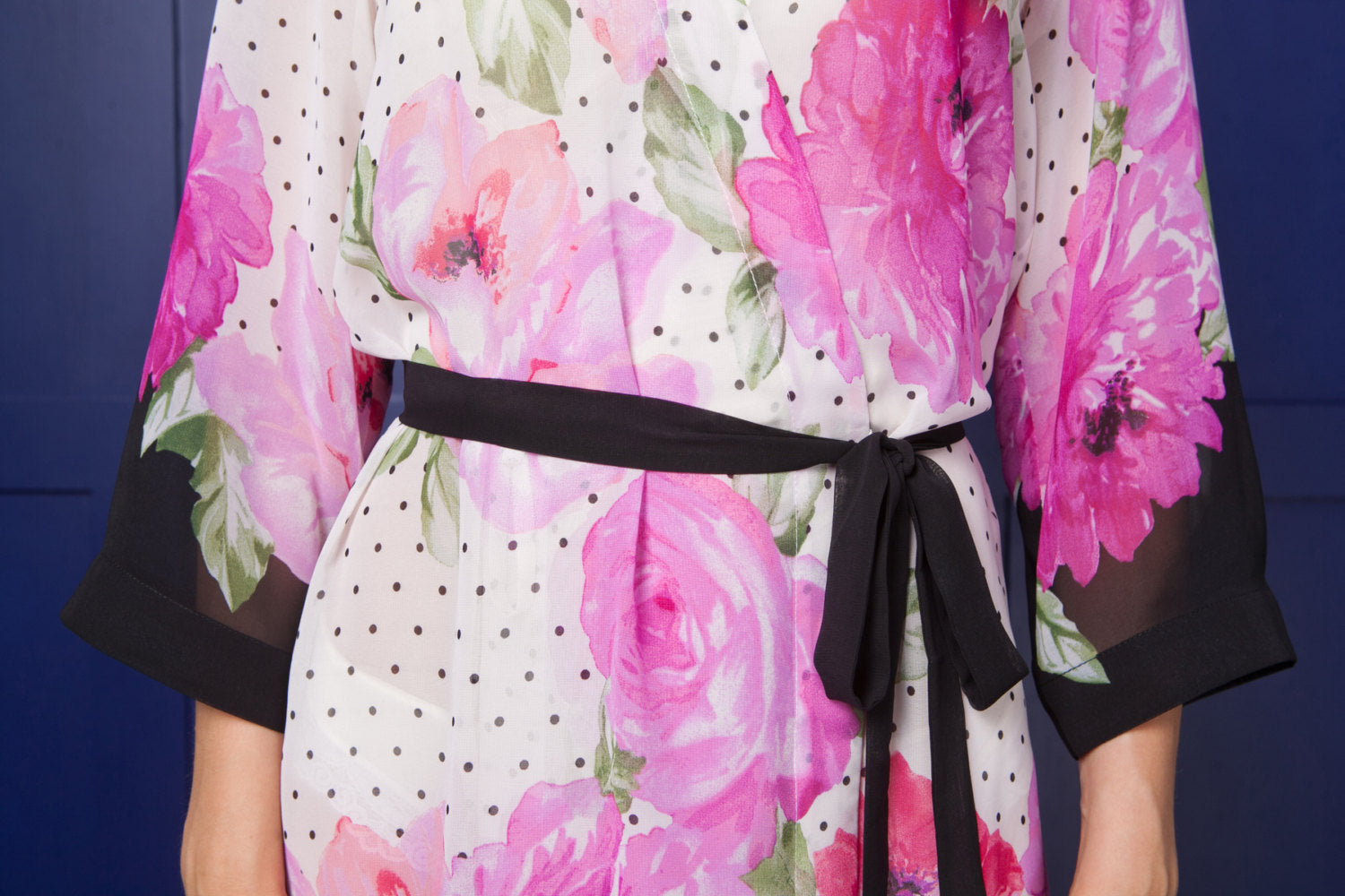 Floral robe with pink flowers and a black belt against a blue background