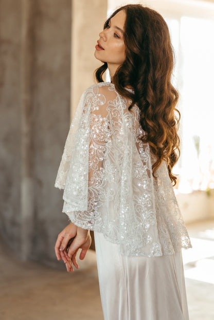 Beaded sequined lace capelet, side view by concrete wall