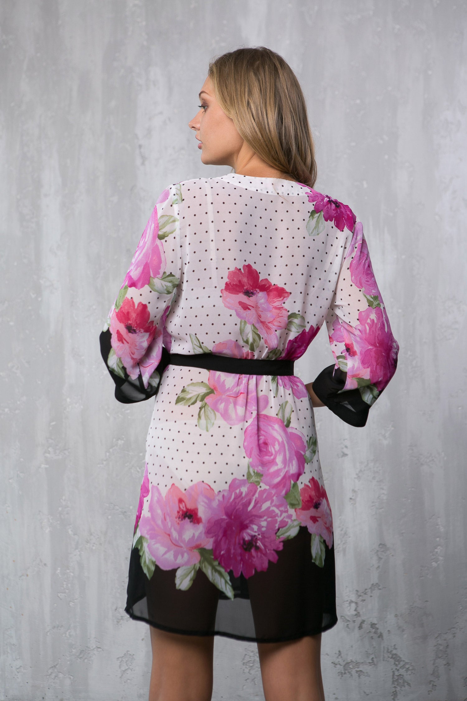 Woman wearing a floral kimono-style garment with a plain background
