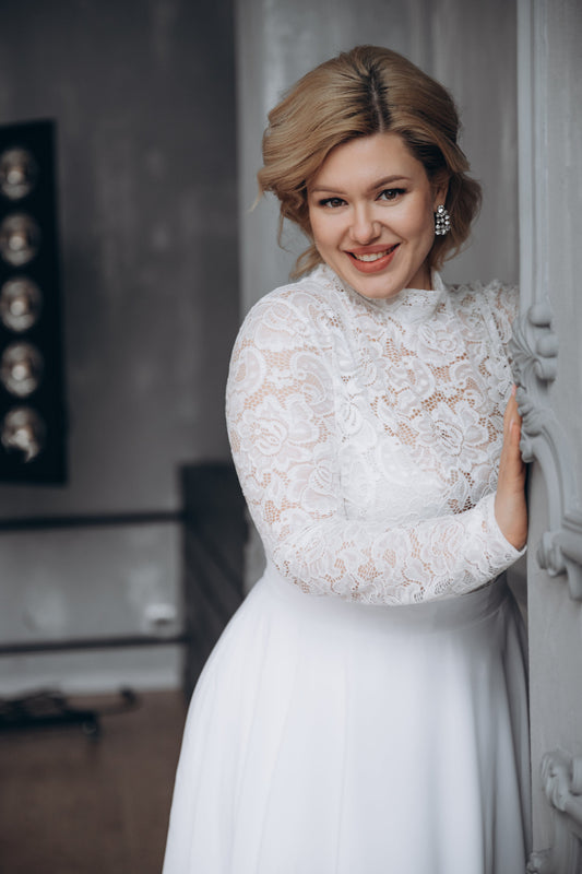 Bride in a white lace top paired with a maxi wedding skirt standing indoors.